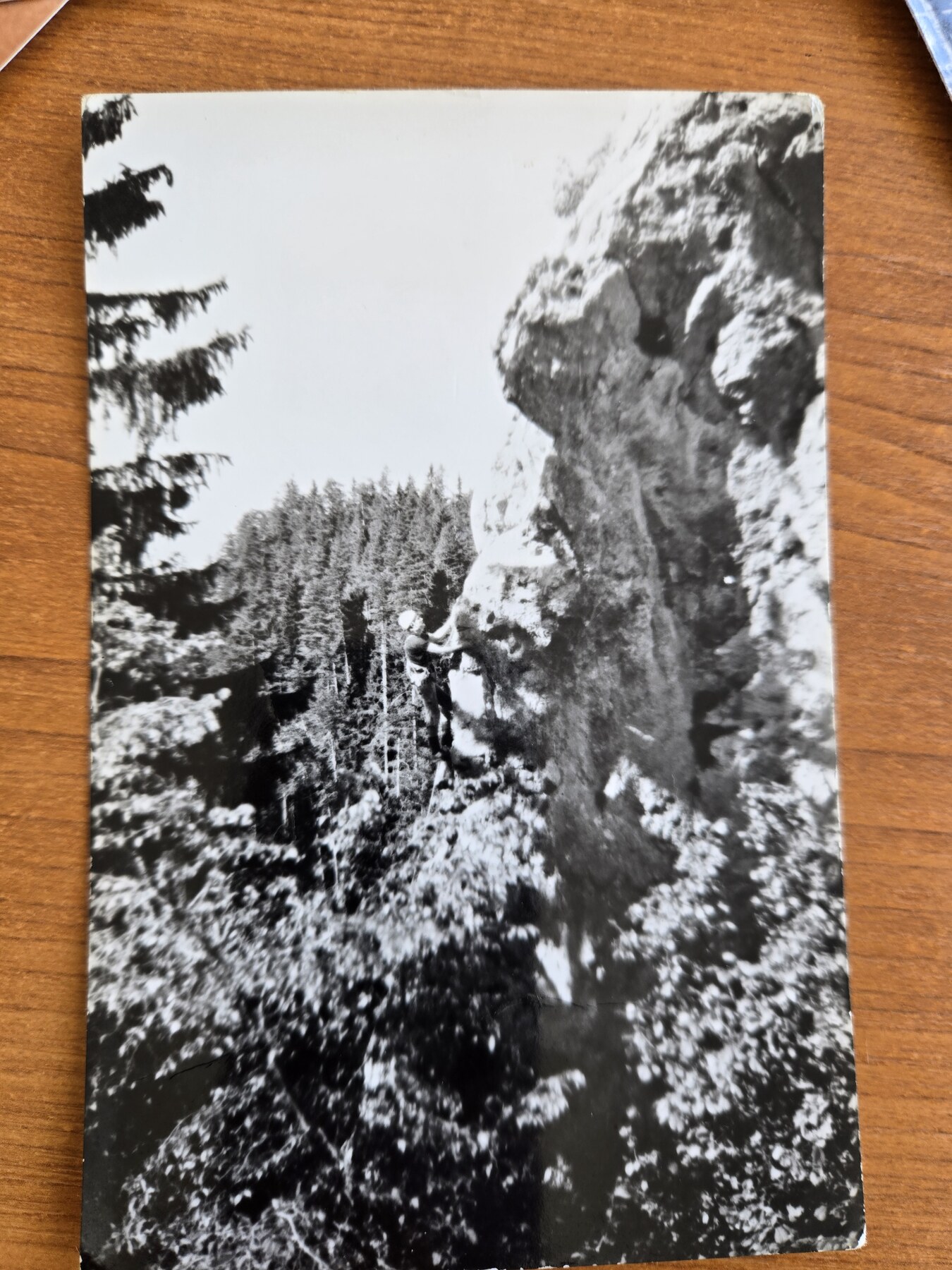 Planinar tokom uspona po stijeni iznad šume na staroj crno-bijeloj fotografiji